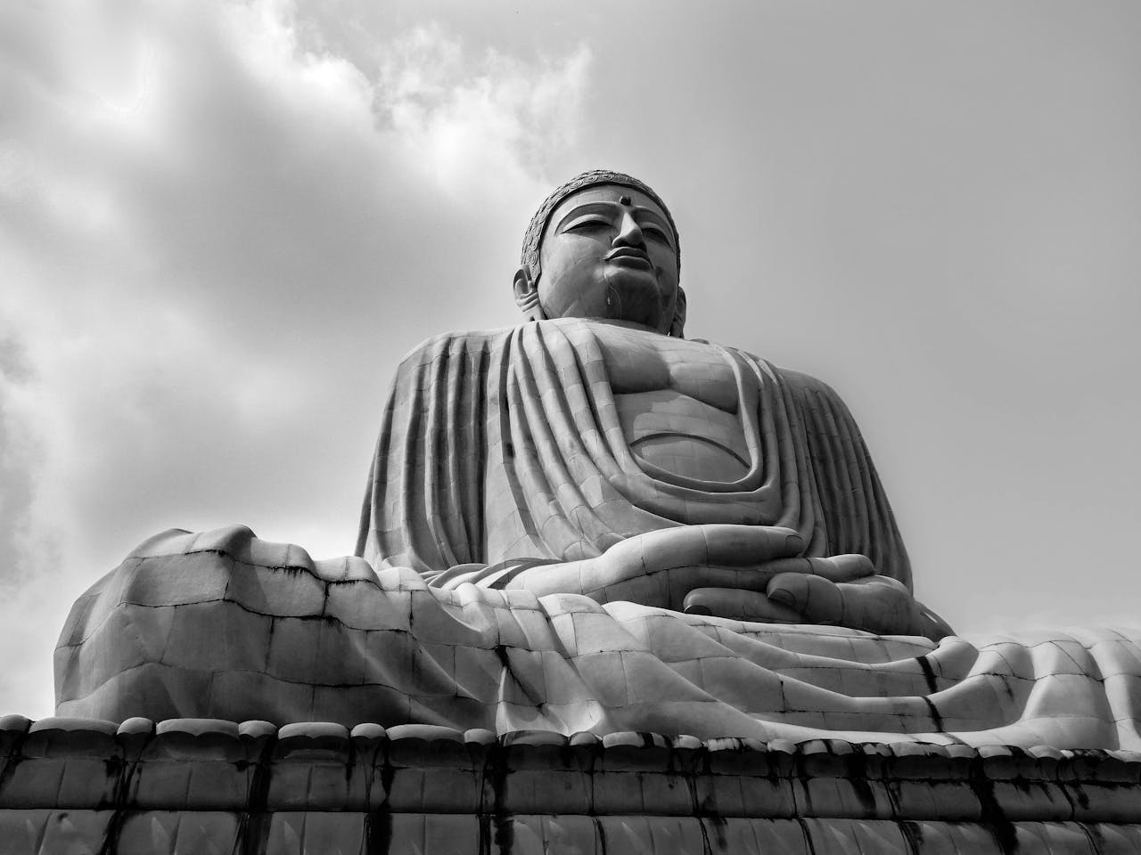 Low angle black and white image of the Great Buddha in Bodh Gaya, symbolizing peace and spirituality.